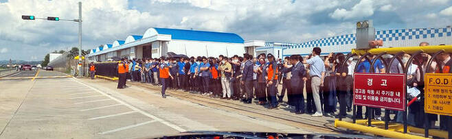 KAI 직원들이 항공기 유도로에서 시험 비행에 나설 KF-21의 등장을 기다리고 있다.