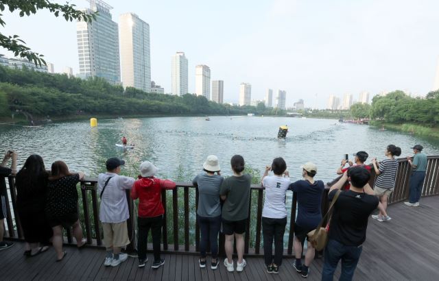 7일 서울 송파구 석촌호수에서 열린 ‘2022 LOTTE Oe Race’ 참가자들의 수영을 시민들이 지켜보고 있다.  이한결 기자
