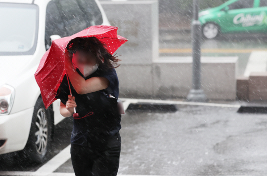 폭염 뒤 다시 장마가 찾아온 8일 서울 영등포구 여의도에 많은 비가 내리며 시민의 손에 쥐어진 우산이 휘어지고 있다. 연합뉴스