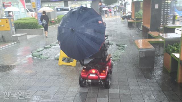 투석 치료를 받고 나온 최두영씨가 비가 쏟아지는 9일 오후 전동휠체어를 타고 서울 동작구 노량진역 앞을 지나가고 있다. 김도형 기자