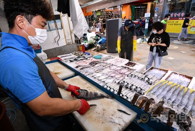 10일 서울 동작구 남성사계시장에서 복구를 마친 생선 가게 상인이 손님에게 팔 생선을 손질하고 있다.