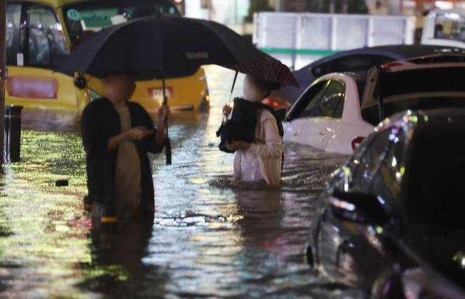 8일 밤 서울 강남구 대치역 인근 도로와 인도가 물에 잠기면서 차량과 보행자들이 통행하는 데 불편을 겪고 있다. (사진=연합뉴스)