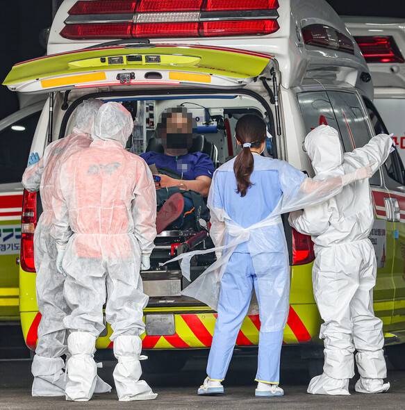 지난 3월 17일 오후 코로나19 전담병원인 서울 중랑구 서울의료원에서 119 구급대원과 의료진이 병원에 도착한 환자를 감염병 전문 병동으로 이송하고 있다. 연합뉴스