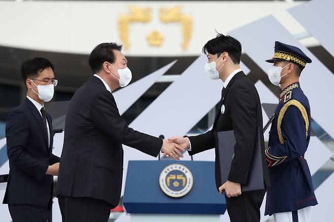 윤석열 대통령이 15일 용산 대통령실 잔디마당에서 열린 제77주년 광복절 경축식에서 고(故) 정두흠 지사에게 건국훈장 애국장을 추서한 뒤 고손자 정창규 씨와 악수하고 있다. /뉴스1