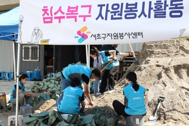 SPC그룹 임직원이 지난 12일 서울 서초구 반포종합운동장에서 하천 범람 방지를 위한 모래주머니를 만들고 있다. SPC그룹 제공