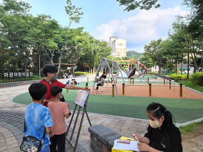 마평어린이공원을 이용한 시민과 어린이들이 이용자 만족도 조사 패널에 스티커를 붙이고 있는 모습. / 사진제공=용인시