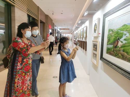 방문객들이 내몽골 싱안맹 농부와 목동 자수 전시회에서 정교한 자수를 보며 감탄하고 있다.