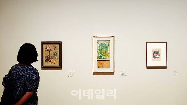 국립현대미술관 ‘이건희컬렉션 특별전: 이중섭’ 전 전경. 한 관람객이 이중섭의 회화작품들을 둘러보고 있다. 왼쪽부터 ‘나무와 까치가 있는 풍경’(1954·40.7×28.3㎝), ‘호박’(1954·39×26.5㎝ & 15.5×25.5㎝), ‘꽃과 손(남덕)’(1953∼1954·26.3×19㎝)가 나란히 걸렸다(사진=오현주 문화전문기자).