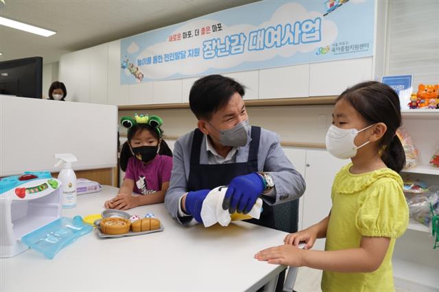박강수(가운데) 서울 마포구청장이 망원장난감대여점에서 아이들과 장난감을 세척하고 있다.마포구 제공