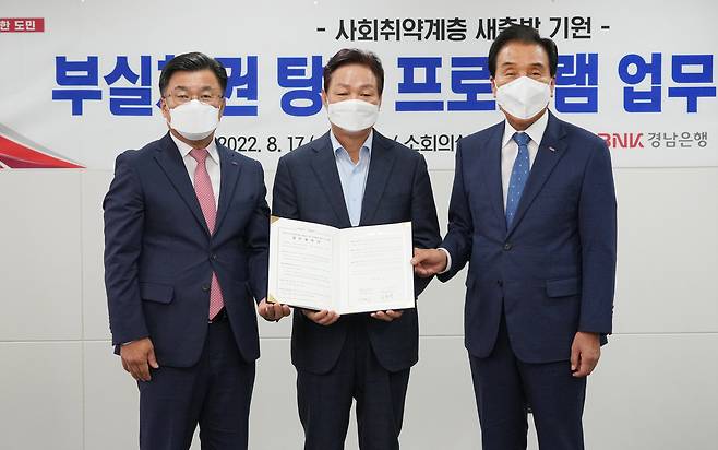 박완수 경남도지사(가운데)와 BNK금융그룹 김지완 회장(오른쪽), BNK경남은행 최홍영 행장이 17일 경남도청에서 경남지역 사회 취약계층 새출발 기원 부실채권 탕감 프로그램 업무협약을 체결한 뒤 기념 사진을 찍고 있다.( BNK경남은행 제공)
