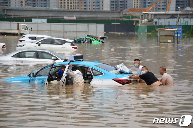 11일(현지시간) 중국 서북지역 간쑤성 란저우에 내린 폭우로 전기차(EV) 충전소가 물에 잠겨 사람들이 택시를 밀고 있다. ⓒ 로이터=뉴스1 ⓒ News1 유민주 기자