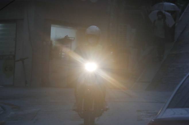 19일 오후 서울 마포구의 한 도로에서 오토바이 운전자가 빗속에서 전조등을 켠 채 서행 운전하고 있다. 이정아 기자