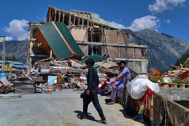 지난달 30일 홍수로 무너진 파키스탄 스왓밸리 칼람 지역의 한 호텔 건물에서 사람들이 멀쩡한 물건을 찾아 수습하고 있다. 파키스탄 재난 당국은 최근 몇 주간 이어진 몬순 우기로 홍수가 발생하면서 50만 명에 육박하는 이재민이 수용소 생활을 하고 있다고 밝혔다.