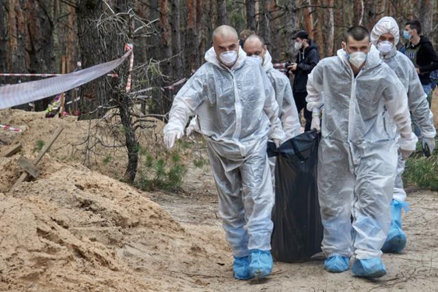 19일 우크라이나 이지움에서 당국자들이 집단 매장지에서 발굴한 시신을 옮기고 있다. 이지움=EPA 연합뉴스