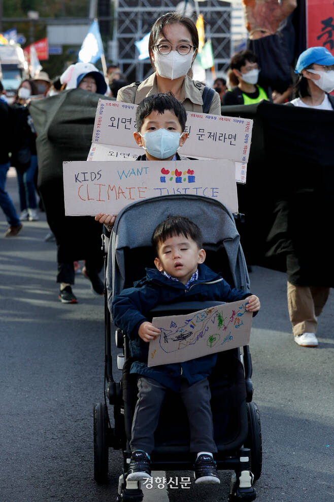 24일 기후정의행진에 참가한 한 여성이 유모차에 탄 자녀와 함께 서울시청 인근에서 기후정의를 요구하며 행진하고 있다. 문재원 기자