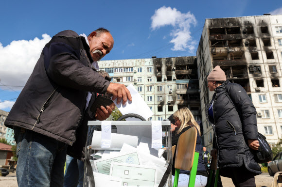 ‘찬성-반대’ 훤히 보이는 투표함 - 러시아에 점령된 우크라이나 4개 지역에서 ‘러시아 영토 편입’을 위한 주민투표가 진행되는 가운데 4곳 중 한 곳인 도네츠크주 마리우폴의 한 주민이 24일(현지시간) 투표함에 용지를 집어넣고 있다. 러시아는 투표 내용이 보이도록 투표용지를 반으로 접지 못하게 하고 투명 플라스틱 재질의 투표함에 넣게 해 사실상 부정선거라는 지적이 제기됐다.마리우폴 타스 연합뉴스