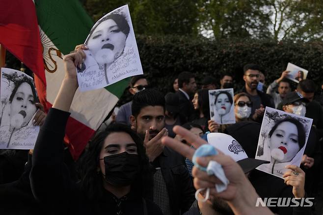 [런던=AP/뉴시스]시위대가 25일(현지시간) 영국 런던의 이란 대사관 밖에서 이란 여성 마흐사 아미니의 사진을 들고 있다. 이들은 아미니가 이란의 엄격한 복장 규정을 위반한 혐의로 종교 경찰에 체포된 데 항의하는 시위를 벌이고 있다. 2022.09.27