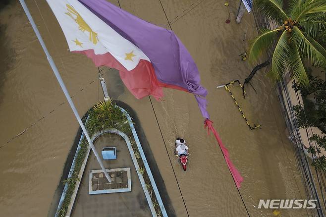 [산미구엘=AP/뉴시스] 26일(현지시간) 필리핀 불라칸주 산미구엘 마을에서 태풍 노루로 인해 침수된 도로 위에 찢겨진 채 펄럭이는 필리핀 국기가 보이고 있다. 2022.09.26.