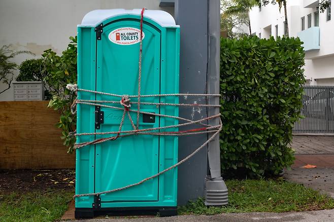 허리케인 '이언'(Ian)이 접근하고 있는 미국 플로리다주 마이애미의 한 이동식 공중화장실이 콘크리트 벽에 고정돼 있다. /연합뉴스
