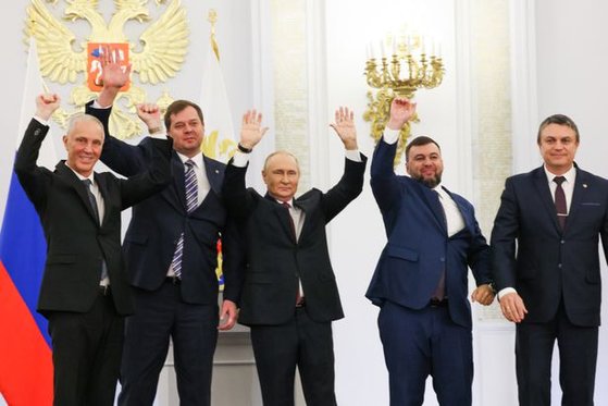 지난달 30일(현지시간) 러시아 모스크바 크렘린궁에서 열린 우크라이나 점령지 합병 조약 서명식이 끝난 뒤 블라디미르 푸틴(가운데) 러시아 대통령이 점령지 괴뢰 정부 대표들과 함께 손을 흔들며 기뻐하고 있다. 로이터=뉴스1