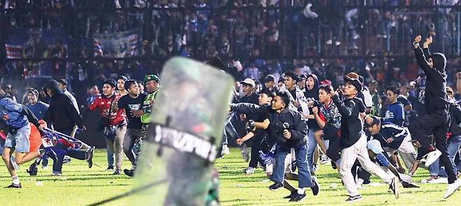 인니, 축구장 관중 폭동… 최소 174명 참사 - 1일(현지시간) 인도네시아 동부 자바 말랑의 축구경기장에서 흥분한 팬들이 그라운드에 난입하고 있다. 인도네시아 정부에 따르면 이날 경기 결과에 분노해 충돌한 양 팀 관중들이 진압에 나선 경찰을 피해 경기장을 빠져나가는 과정에서 경찰을 포함해 최소 174명이 숨지고 180명 이상이 다쳤다.말랑 AP 연합뉴스