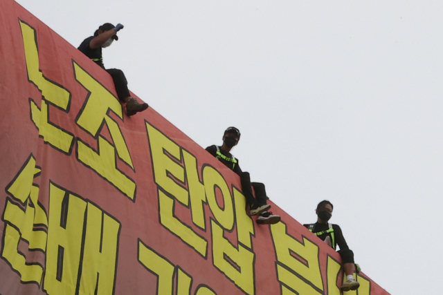 8월 18일 하이트진로에서 고공농성을 했던 화물노동자들이 노조원들의 격려에 호응하고 있다. 연합뉴스