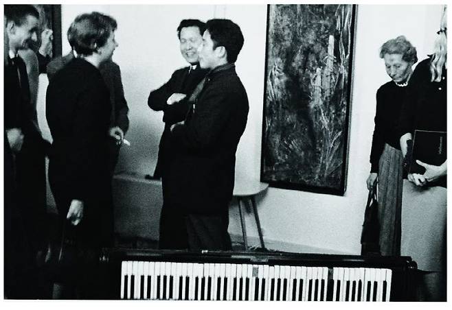 존 케이지를 만나 새로운 예술에 눈을 뜬 백남준은 케이지에게 바치는 퍼포먼스를 기획, 실행했다. 이를 만프레드 레베가 사진으로 기록했다. 뒤에 보이는 작품은 만프레드 레베의 ‘존 케이지에 대한 경의: 테이프와 피아노를 위한 음악’(갤러리 22, 뒤셀도르프, 20.3×25.4cm, 1959).(사진=백남준아트센터)