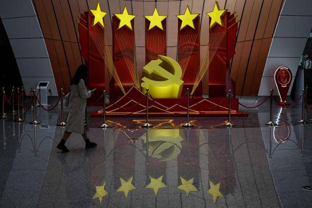 중국 공산당 20차 전국대표대회(당대회)를 이틀 앞둔 14일 한 중국 시민이 베이징 다싱국제공항에 설치된 중국 공산당 상징 조형물 앞을 지나고 있다. 베이징=AFP 연합뉴스