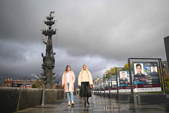 현지시간 19일 모스크바 한 공원에서 여성들이 러시아 군인들을 기리는 포스터 옆을 지나고 있다. 〈사진=AFP 연합뉴스〉