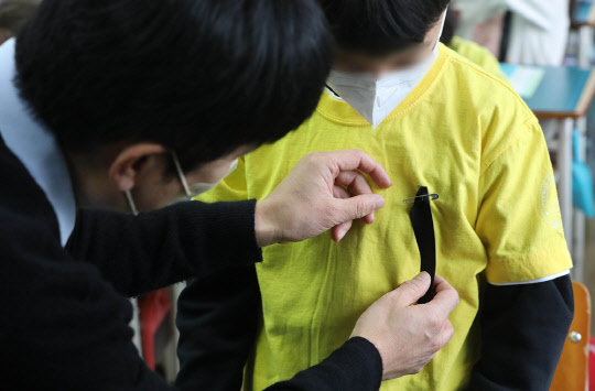 1일 오전 서울 용산구의 한 초등학교에서 선생님이 학생에게 이태원 참사 희생자를 추모하는 검은리본을 달아주고 있다.<공동취재>