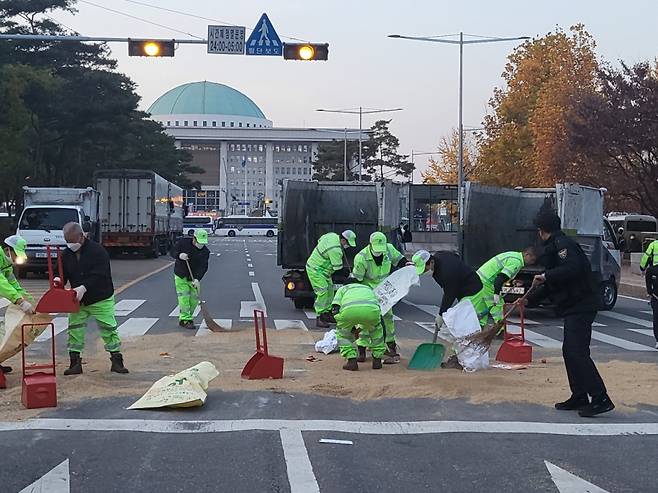 16일 오후 5시쯤 서울 여의도 국회 앞. 전국농민회총연맹 등 8개 농민 단체가 뿌리고 간 쌀나락을 환경미화원들이 치우고 있는 모습./사진=김미루 기자