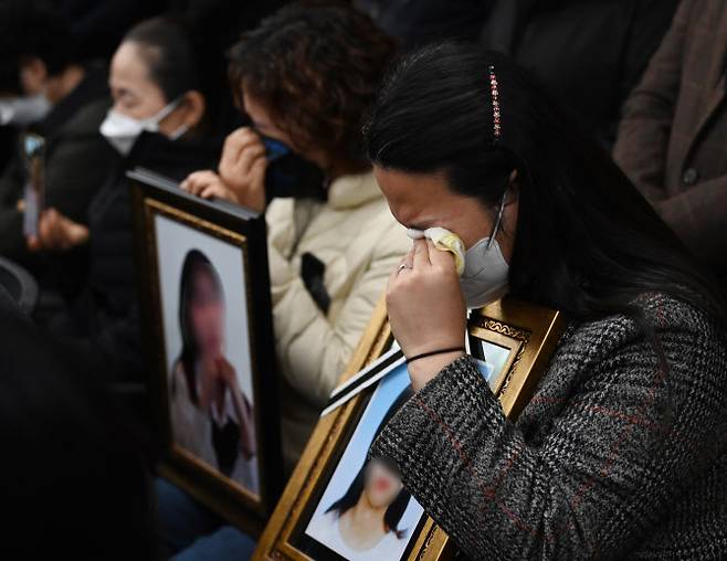이태원 참사 유가족들이 기자회견장에서 희생자들의 영정을 들고 눈물을 닦고 있다 (사진=공동취재단)