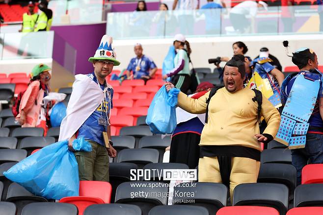 ▲ 2022 카타르 월드컵 코스타리카전이 끝난 뒤 경기장을 청소하는 일본 팬들, 한 팬은 청소하는 자신들을 내세우려는 듯 쓰레기 봉지를 보여주고 있다.