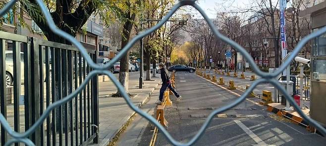30일 오전 중국 베이징 차오양구의 한 아파트 철망 안으로 시민이 지나가고 있다. 사진 = 정지우 특파원