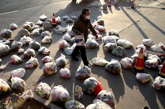 지난달 29일 중국 산시성 시안의 한 도로. 한 남성이 주민들에게 나눠줄 식료품을 준비하고 있다. [로이터=연합뉴스]