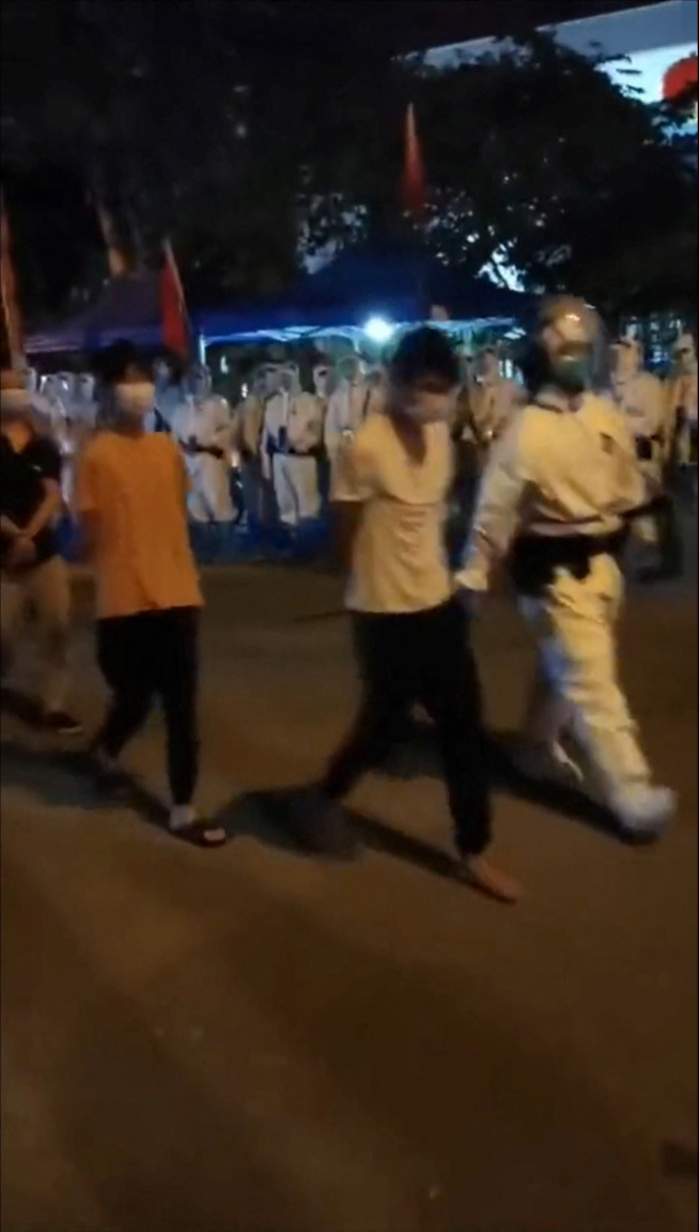 방역복을 입은 경찰이 30일 중국 광둥성 광저우에서 열린 코로나19 방역 반대 시위 도중 체포한 시위대를 연행하고 있다. 로이터연합.