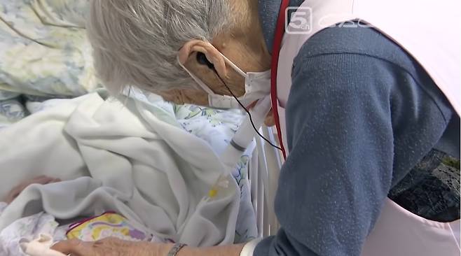 실버주택 입소자들은 이케다씨보다 모두 젊다. 97세 이케다씨가 침대에서 움직이지 못하는 78세 환자에게 위에 꽂힌 튜브로 영양분을 공급해 주고 있다.