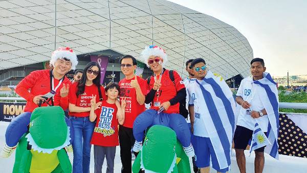 정지원(왼쪽 네 번째) 카타르한인교회 목사와 성도들이 지난달 24일 대한민국과 우루과이 전이 열린 도하 에듀케이션시티 스타디움에서 우루과이 응원단과 경기 전 기념촬영을 하고 있다. 카타르한인교회 제공