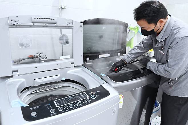 LG전자 직원이 사회복지시설에서 세탁통에 스팀을 분사하는 통살균 서비스를 진행하고 있다. [자료:LG전자]