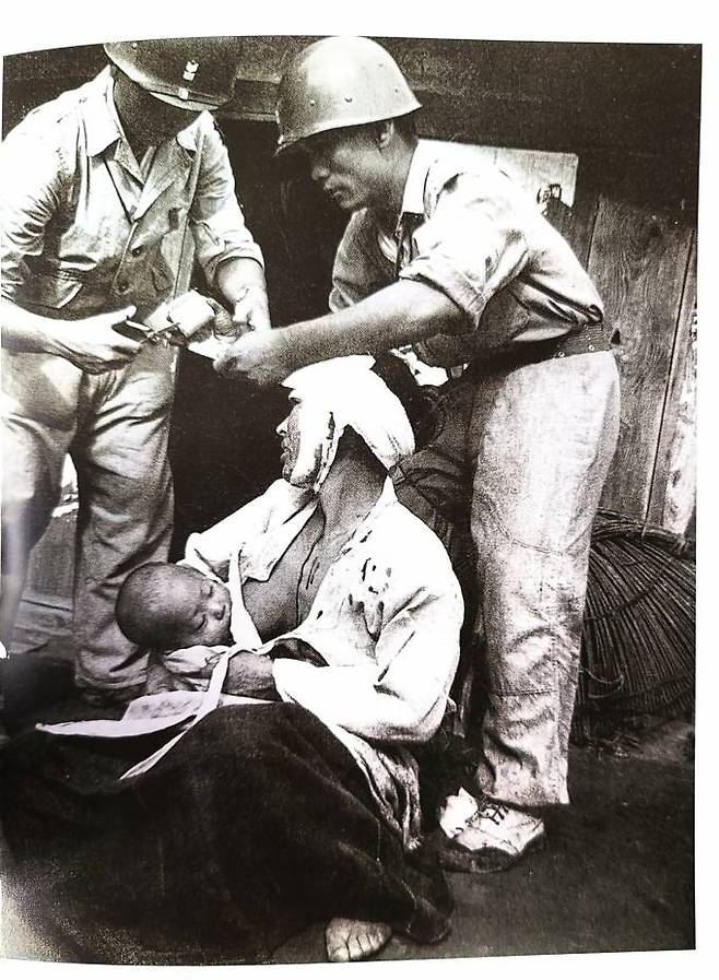 6⋅25전쟁 참상 사진. 한 어머니가 머리를 다친 채 치료를 받으며 자식에게 젖을 물리고 있다.