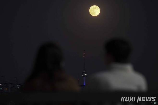 2022년 마지막 보름달이 떠오른 8일 오후 서울 영등포구 여의도 한강공원을 찾은 한 커플이 보름달을 보고 있다.