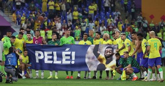 브라질 선수들이 6일 카타르 도하 974 스타디움에서 열린 카타르월드컵 16강전 한국과 경기에서 4-1 승리한 후, 투병 중인 펠레의 쾌유를 기원하는 현수막을 펼치고 있다. 연합뉴스