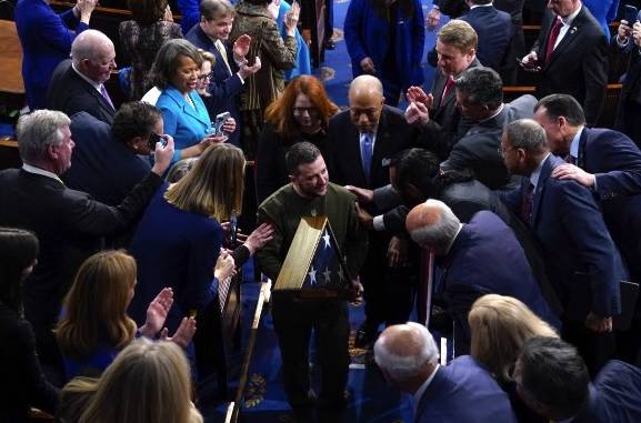 21일(현지시간) 미국 연방의회 의사당 본회의장에서 연설을 마치고 퇴장하는 볼로디미르 젤렌스키 우크라이나 대통령(가운데)을 향해 상하 양원 의원들이 기립박수를 보내고 있다. 워싱턴=AP연합뉴스