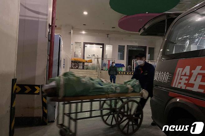 22일(현지시간) 코로나19 확산 속 중국 충칭의 화장장에서 장례 직원이 화장할 시신을 카트에 실려 옮겨지고 있다. ⓒ AFP=뉴스1 ⓒ News1 우동명 기자