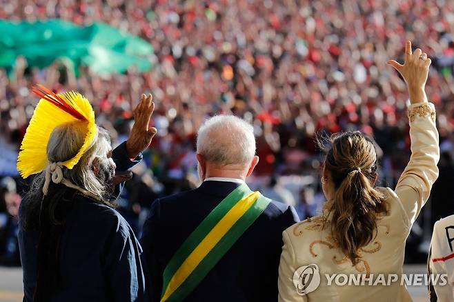 '국기 색' 대통령 띠 두르고 지지자에게 인사하는 룰라 대통령 (브라질리아 AFP=연합뉴스) 루이스 이나시우 룰라 다시우바 브라질 대통령(가운데)이 1일(현지시간) 브라질리아에서 열린 대통령 취임식에서 대통령 띠를 두른 채 영부인(오른쪽) 등과 함께 지자에게 인사하고 있다. 2022.1.2