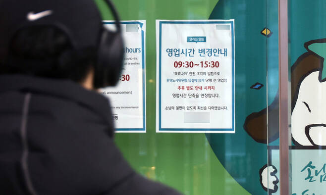지난 24일 서울 시내 한 은행 자동화기기 점포에 코로나19 안전조치에 따른 영업시간 조정 안내문이 붙어 있다. 연합뉴스