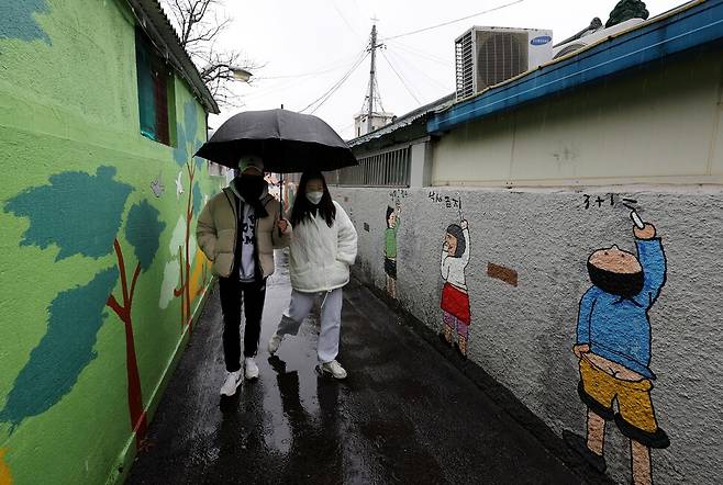 우산을 함께 쓴 연인이 강릉시 임당동 벽화골목을 지나고 있다. 이 골목의 이름은 ‘소풍 가는 길’이다.