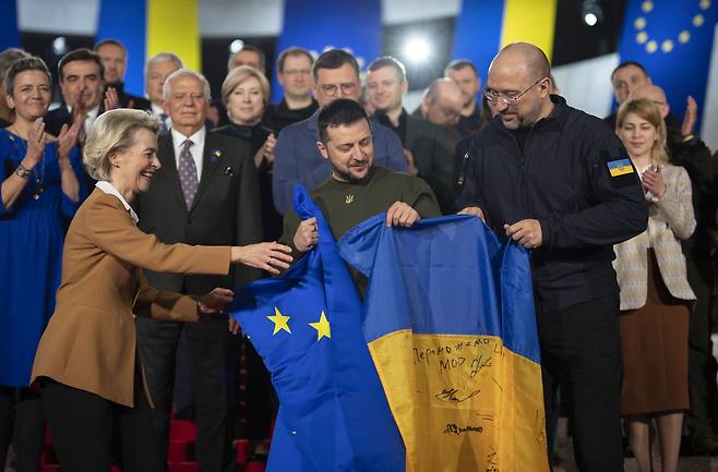 지난 2일(현지 시각) 우크라이나 수도 키이우에서 볼로디미르 젤렌스키(가운데) 우크라이나 대통령과 우르줄라 폰데어라이엔(왼쪽) 유럽연합(EU) 집행위원장, 데니스 슈미할(오른쪽) 우크라이나 총리가 기념사진 촬영에 앞서 유럽기와 우크라이나 국기를 펼치고 있다. 이날 EU는 우크라이나에 총 5억유로(약 6700억원) 상당의 군사 지원을 약속했다. 3일 EU·우크라이나 정상회담에서는 우크라이나의 EU 회원국 합류 문제가 논의됐다. /EPA 연합뉴스