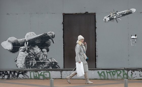 지난달 우크라이나 수도 키이우의 모습. 대전차 미사일을 발사하는 우크라이나 군인 그림이 그려진 벽 앞을 한 우크라이나 여성이 지나고 있다. EPA=연합뉴스