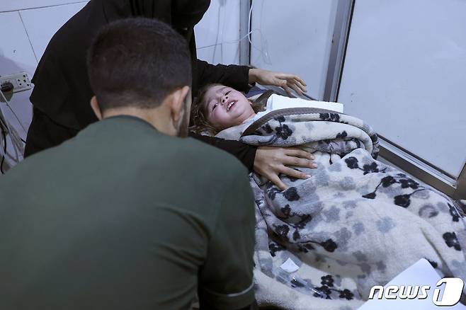 6일(현지시간) 시리아 잔다리스 마을에서 구조된 한 어린 아이가 병원 침상에 누워 구조 대원을 바라보고 있다. 이날 새벽 사람들이 잠든 사이 시리아를 강타한 지진으로 현장에서는 정확한 사망자 수를 집계할 수 없을 정도로 큰 인명피해가 발생했다. ⓒ AFP=뉴스1 ⓒ News1 권진영 기자